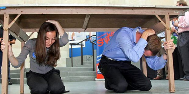 Participants take part in a Great ShakeOut Earthquake Drill by hiding under a table. (Facebook/Grea...