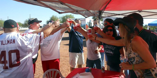 A group of Arizona Cardinals fans participate in a large cheering with alcoholic beverages in hand ...