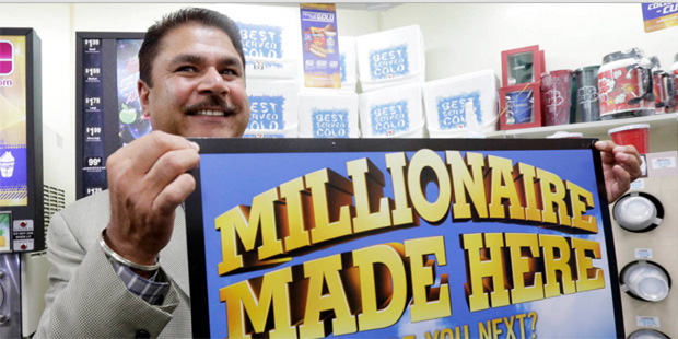 Balbir Atwal, the owner of a 7-Eleven store that sold a winning Powerball lottery ticket, holds up ...