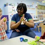 Michou Tshiala, a Congolese refugee from Zambia, center, helps children Zachary Jones, 4, left, and Logan Kelley, 4, sculpt play dough March 3, 2016, at the Eastside YMCA Early Care and Enrichment Program in Harborcreek Township, Pa. Tshiala, who arrived in the United States in June of 2014, recently began working in the childcare program after graduating from the Erie Art Museum's Old Songs New Opportunities program. The program trains former refugees who now live in Erie to work in early learning centers and to use their traditional children's songs on the job.  (Sarah Crosby/Erie Times-News via AP)
