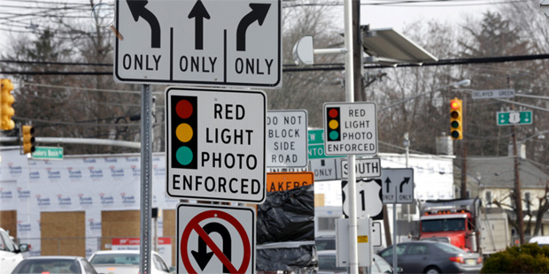 FILE - In a Tuesday, Dec. 16, 2014 file photo, traffic passes a red light photo enforcement sign be...