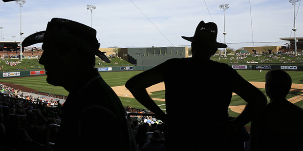 Fans take a break from the sun during seventh inning of a spring baseball game between the Arizona ...
