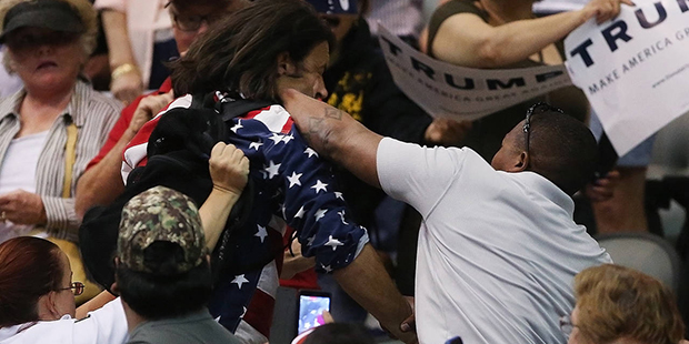 Trump protester Bryan Sanders, center left, is punched by a Trump supporter as he is escorted out o...