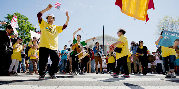 Supporters of fair immigration reform dance in front of the Supreme Court in Washington, Monday, Ap...