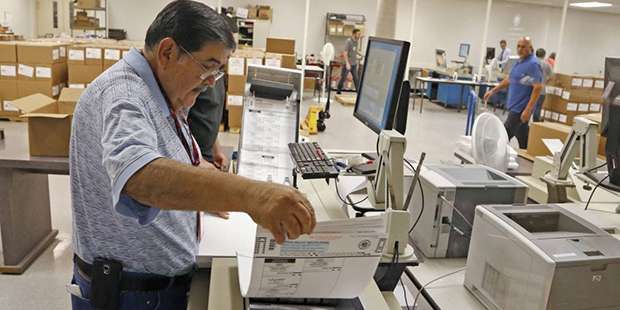 An Arizona elections official at the Maricopa County Recorder's Office inserts ballots into a machi...