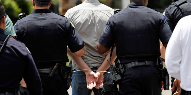 Phoenix police officers walk an arrested protester to a squad car Thursday June 23, 2016, in Phoeni...