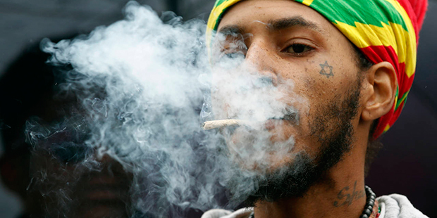 Jerome Waite, known by his spiritual name Rasfia, smokes a marijuana cigarette, during a rally to s...