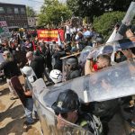 White nationalist demonstrators use shields as they clash with counter demonstrators at the entrance to Lee Park in Charlottesville, Va., Saturday, Aug. 12, 2017.   Hundreds of people chanted, threw punches, hurled water bottles and unleashed chemical sprays on each other Saturday after violence erupted at a white nationalist rally in Virginia. At least one person was arrested.  (AP Photo/Steve Helber)