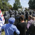 White nationalist demonstrators hold their ground against Virginia State Police as police fire tear gas rounds in Lee Park in Charlottesville, Va., Saturday, Aug. 12, 2017.  Gov. Terry McAuliffe declared a state of emergency and police dressed in riot gear ordered people to disperse after chaotic violent clashes between white nationalists and counter protestors. (AP Photo/Steve Helber)