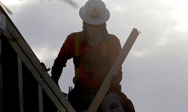 A construction worker at dawn with a face and neck covering to avoid the heat, Tuesday, June 20, 20...