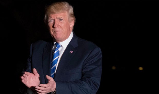 President Donald Trump claps as he walks across the South Lawn on his return to the White House in ...