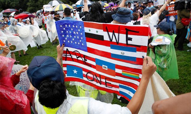 A woman holds a sign declaring one nation of immigrants, during a rally in favor of DACA and immigr...