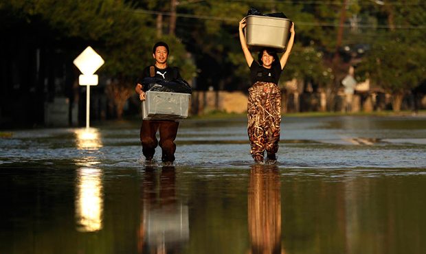 Mariko Shimmi, right, helps carry items out of the home of Ken Tani in a neighborhood still flooded...