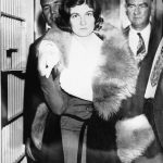 Winnie Ruth Judd, confessed slayer of two women, whose bodies were recovered from trunks shipped from Phoenix, Ariz., to Los Angeles, leaves the emergency police hospital, Oct. 23, 1931, a few hours after her voluntary surrender. At her side stands the Los Angeles Chief of Detectives, Joseph Taylor. Between them, rear, is Judd's husband, Dr. W.C. Judd.  Mrs. Judd's left arm is in a sling, a bullet - which she claims was inflicted by one of her victims - having just been removed from her left hand. (AP Photo)