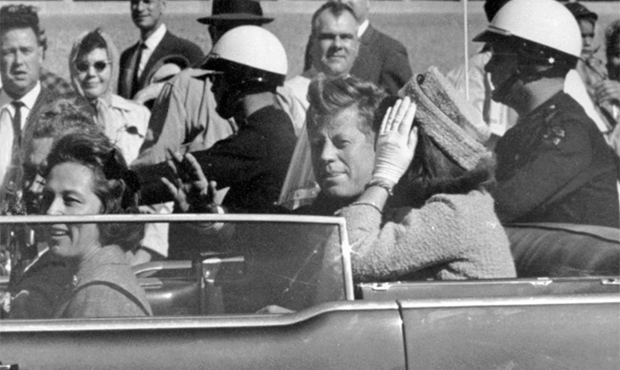 FILE - In this Nov. 22, 1963 file photo, President John F. Kennedy waves from his car in a motorcad...
