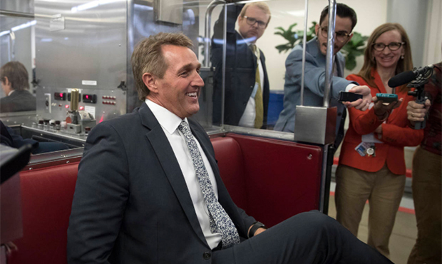 Sen. Jeff Flake, R-Ariz., talks with media as he boards the subway on Capitol Hill in Washington, T...