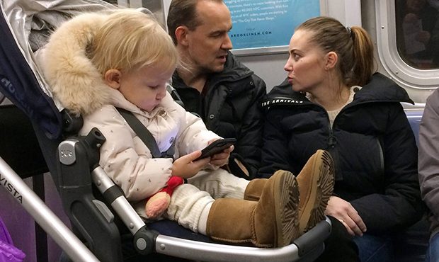 In this Dec. 17, 2017, photo, a baby girl plays with a mobile phone while riding in a New York subw...
