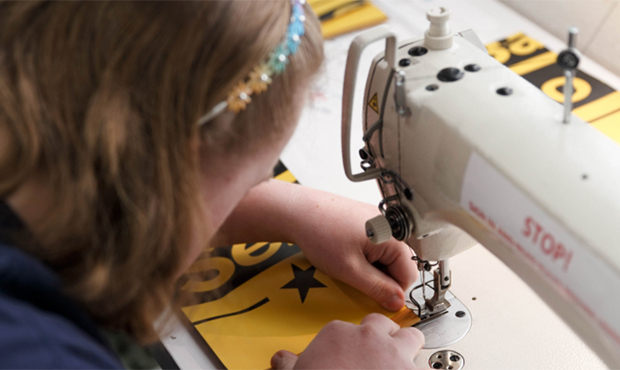 Madison Ryan, who learned how to sew only a month ago, sews the side panels for a new backpack desi...