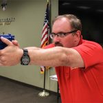 Firearms instructor Ryan Arnold, using a blue plastic gun, at a class teaching children and families how to safely handle weapons. (Photo by Melina Zuniga/Cronkite News)