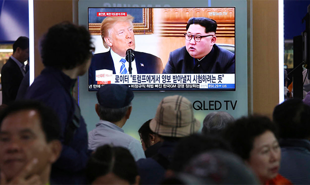 People watch a TV screen showing file footage of U.S. President Donald Trump, left, and North Korea...