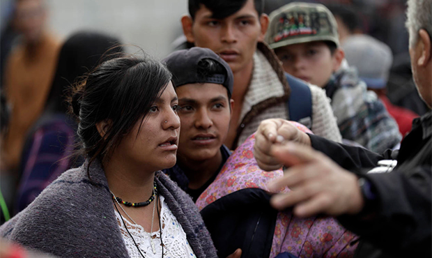 Central American migrants listen to directions as they wait in line for a meal at a shelter in Tiju...