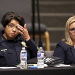 Phoenix Police Chief Jeri Williams, left, and Mayor Kate Gallego, right, listen to a speaker at a community meeting, Tuesday, June 18, 2019, in Phoenix. The community meeting stems from reaction to a videotaped encounter that surfaced recently of Dravon Ames and his pregnant fiancee, Iesha Harper, having had guns aimed at them by Phoenix police during a response to a shoplifting report, as well as the issue of recent police-involved shootings in the community. (AP Photo/Ross D. Franklin)