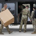 Members of an Arizona National Guard unit load up a Black Hawk helicopter to deliver medical supplies to the remote Navajo Nation town of Kayenta due to the coronavirus, Tuesday, March 31, 2020, in Phoenix. (AP Photo/Ross D. Franklin)