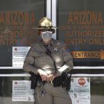 A Department of Public Safety police officer stands in front of the Arizona House of Representatives building as protesters rally at the state Capitol to 're-open' Arizona against the governor's stay-at-home order due to the coronavirus Monday, April 20, 2020, in Phoenix. (AP Photo/Ross D. Franklin)