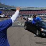 Ben Rodriguez, the principal at Buckeye Union High School, waves to graduates during tjeh Parade of Graduates a drive-thru graduation ceremony on the race track at Phoenix Raceway Saturday, May 16, 2020, in Avondale, Ariz. The coronavirus has caused most schools to either cancel traditional graduations or find alternative celebrations. (AP Photo/Ross D. Franklin)