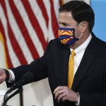 
              Arizona Republican Gov. Doug Ducey uses hand sanitizer as he wears a face covering prior to speaking about the latest coronavirus data at a news conference Thursday, June 25, 2020, in Phoenix. (AP Photo/Ross D. Franklin, Pool)
            