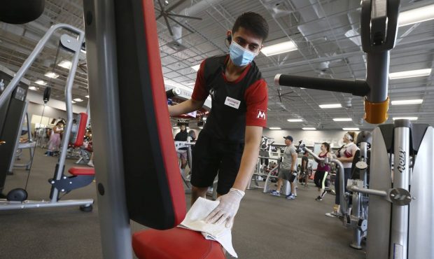 Jeremy Zepeda, a front desk associate at Mountainside Fitness, disinfects workout equipment Thursda...