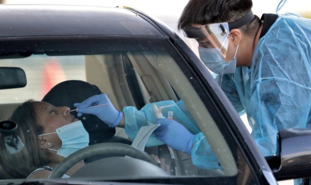 FILE - In this June 27, 2020, file photo, people are tested in their in vehicles in Phoenix's weste...