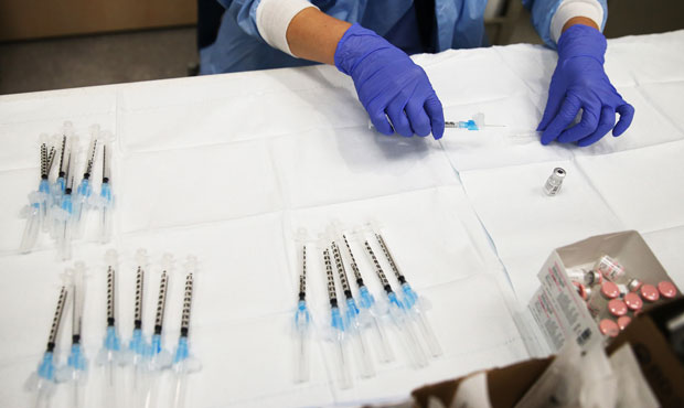 A pharmacy technician prepares a dose of the COVID-19 Pfizer vaccine to be administered to a patien...