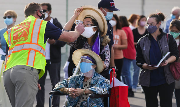 People receive temperature checks as they wait in line to receive the COVID-19 vaccine at a mass va...