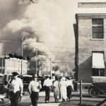 
              FILE - In this photo provided by Department of Special Collections, McFarlin Library, The University of Tulsa, two armed men walk away from burning buildings as others walk in the opposite direction during the June 1, 1921, Tulsa Race Massacre in Tulsa, Okla. (Department of Special Collections, McFarlin Library, The University of Tulsa via AP, File)
            