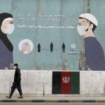 
              A man wearing a protective face mask to help curb the spread of the coronavirus, walks past a painted wall of Ministry of Public Health, which guides social distancing in Kabul, Afghanistan, Saturday, May 29, 2021. (AP Photo/Rahmat Gul)
            