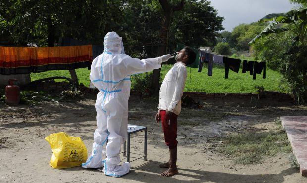 A health worker in protective suit takes a nasal swab sample of a man to test for COVID-19 in Kuseh...