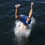 
              A person dives into the water from a pedestrian bridge at Lake Union Park into the water during a heat wave hitting the Pacific Northwest, Sunday, June 27, 2021, in Seattle. Yesterday set a record high for the day with more record highs expected today and Monday. (AP Photo/John Froschauer)
            