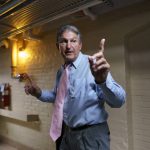 Sen. Joe Manchin, D-W.Va., a key infrastructure negotiator, signals to his staff as he works behind closed doors with other Democrats in a basement room at the Capitol in Washington, Wednesday, June 16, 2021. (AP Photo/J. Scott Applewhite)