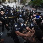 
              Police officers and protesters clash near CNN Center, May 29, 2020, in Atlanta, in response to George Floyd's death. The protest started peacefully earlier in the day before demonstrators clashed with police. The image was part of a series of photographs by The Associated Press that won the 2021 Pulitzer Prize for breaking news photography. (AP Photo/Mike Stewart)
            