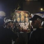
              Israeli police officers stand guard as right wing protesters chant slogans and hold signs showing Naftali Bennett, and other members of the Yamina party, with Arab politicians Ahmad Tibi, right, and Mansour Abbas, left, during a demonstration in the central Israeli city of Ramat Gan, Wednesday, June 2, 2021. Hebrew sign reads, "Don't form a left government with supporters of terror." (AP Photo/Sebastian Scheiner)
            