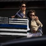 
              Susan Gilmore and her son Gil Gilmore, 10, pay their respects as hundreds of law enforcement and first responder vehicles pass by during a funeral procession for slain Arvada police officer Gordon Beesley in Lafayette, Colo., on Tuesday, June 29, 2021. A funeral was held at the Flatirons Community Church for officer Beesley, who was a 19-year veteran of the Arvada Police Department. Officer Beesley was killed by a gunman in Olde Town Arvada plaza on June 21, 2021. (Chancey Bush/The Gazette via AP)
            