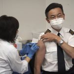 Satoru Shimizu, a 56-year-old All Nippon Airlines pilot, takes Moderna's COVID-19 vaccine shot in Haneda Airport as the airline company began its workplace vaccination in Tokyo, on Sunday, June 13, 2021. (AP Photo/Kantaro Komiya)
