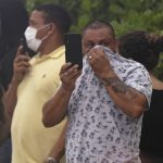 
              Bystanders cover their faces at the Champlain Towers South Condo as thick smoke from a fire within the rubble fills the air in Surfside, Fla., Friday, June 25, 2021. The apartment building partially collapsed on Thursday, June 24. (AP Photo/Wilfredo Lee)
            