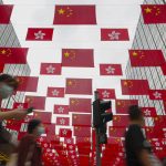 
              People walk past China national flags and Hong Kong flags for the celebration of 24th anniversary of Hong Kong handover to China at a shopping district in Hong Kong, Sunday, June 27, 2021. Fung Wai-kong, an editorial writer of the now-defunct Hong Kong pro-democracy newspaper Apple Daily was arrested at the airport on Sunday night while attempting to leave the city, local media reported Sunday. (AP Photo/Vincent Yu)
            