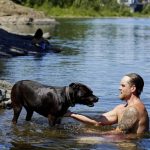 
              Justin Swanner and his dog Havoc swim in the Clackamas River to escape from the heat during a record setting heat wave in Oregon City, Ore., Sunday, June 27, 2021. Yesterday set a record high for the day with more records expected today. (AP Photo/Craig Mitchelldyer)
            