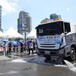 
              A truck sprays water to cool a hot street as people holding umbrellas queue in line to wait to get coronavirus testing while holding umbrellas at a makeshift testing site in Seoul, South Korea, Monday, July 26, 2021. A banner reads "Spraying water on the street due to the heat wave." (AP Photo/Ahn Young-joon)
            