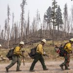 
              Firefighters from New Mexico walk toward the Northwest edge of the Bootleg Fire while working to build a containment line on Friday, July 23, 2021, near Paisley, Ore. (AP Photo/Nathan Howard)
            