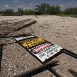 
              Ashley Williams Watt walks across the site of an abandoned well at her ranch, Friday, July 9, 2021, near Crane, Texas. Some of her wells are leaking chemicals such as benzene, a known carcinogen, into fields and drinking water. (AP Photo/Eric Gay)
            