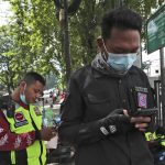 
              Motorcycle volunteers Hendi and Rofiq Nur check their mobile phone as they take a break in Bekasi on the outskirts of Jakarta, Indonesia on July 11, 2021. The two-wheeled volunteers provide a key service in the sprawling metropolis, one in more need than ever as ambulances struggle to serve all those in need because of a surge in coronavirus infections and deaths. (AP Photo/Achmad Ibrahim)
            